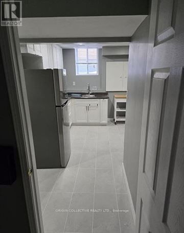 Clarington (Courtice) apartment for rent - A kitchen with white cabinets and a black refrigerator.