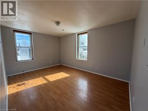 Watford apartment for rent - A room with wooden flooring and two windows.