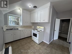 Warwick (Watford) fourplex for rent - A kitchen with white cabinets and a stove top oven.