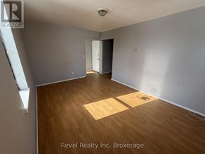 Warwick (Watford) fourplex for rent - A room with wooden flooring and white walls, with a door on the right side.