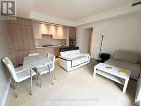 Toronto (Church-Yonge Corridor) condo for rent - A living room with a white couch, a white coffee table, and a dining table with chairs.