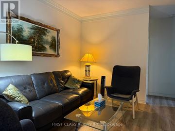 Toronto (University) fourplex for rent - A black leather couch sits in a living room with a lamp and a painting on the wall.