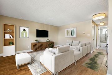 Denver apartment for rent - A living room with a white couch and a TV on the wall.