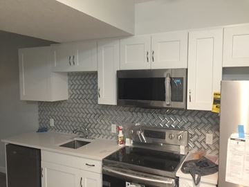 Edmonton apartment for rent - A kitchen with white cabinets and a black dishwasher.