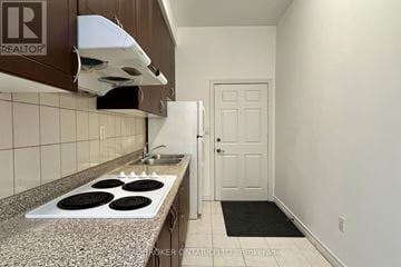 Toronto (Greenwood-Coxwell) apartment for rent - A kitchen with a stove top oven and a broker logo.