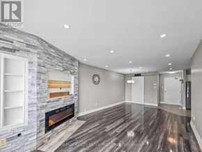 Barrie (Alliance) condo for rent - A stone fireplace with a wood mantle is in a room with wood flooring.