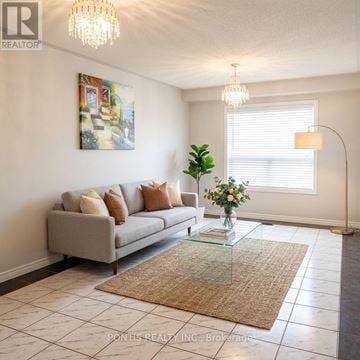 Mississauga (Central Erin Mills) apartment for rent - A living room with a grey couch, a glass coffee table, and a painting on the wall.