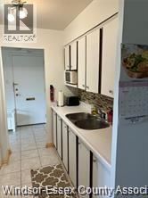 Windsor condo for rent - A kitchen with white cabinets and a black counter top.