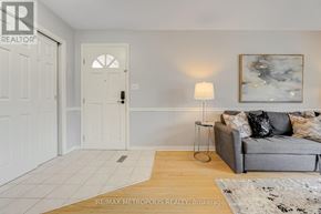 Oshawa (Mclaughlin) apartment for rent - A living room with a grey couch, a white door, and a painting on the wall.