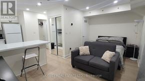 Toronto (Cabbagetown-South St. James Town) townhouse for rent - A real estate listing image of a bedroom with a bed, couch, and desk.