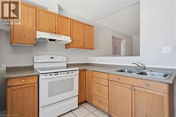 Kitchener townhouse for rent - A kitchen with wooden cabinets and a white stove top oven.