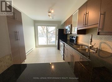 Ottawa condo for rent - A kitchen with brown cabinets and a black stove top.