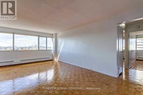 Toronto (Flemingdon Park) condo for rent - A large empty room with wooden flooring and a view of the city through the windows.