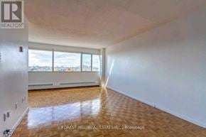 Toronto (Flemingdon Park) condo for rent - A large empty room with wooden flooring and a window overlooking a cityscape.