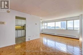 Toronto (Flemingdon Park) condo for rent - A spacious room with wooden flooring and a view of the city through large windows.