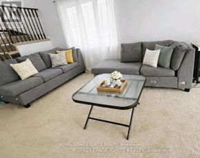 Ajax (Northeast Ajax) apartment for rent - A living room with two grey couches, a glass coffee table, and a small table with a vase of flowers.