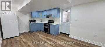 Oshawa (Eastdale) apartment for rent - A kitchen with blue cabinets and a white refrigerator.