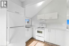 Hamilton apartment for rent - A white kitchen with a refrigerator, oven, and cabinets.