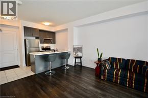Waterdown condo for rent - A living room with a striped couch and a kitchen area in the background.