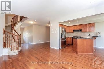 Ottawa townhouse for rent - A well-lit kitchen with wooden cabinets and a staircase on the left side.