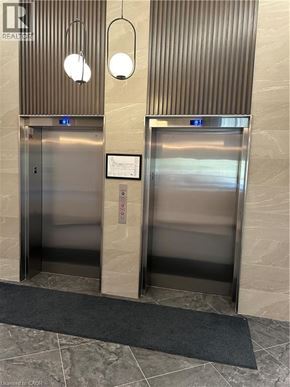 Kitchener condo for rent - Two elevators in a building with a sign on the wall.