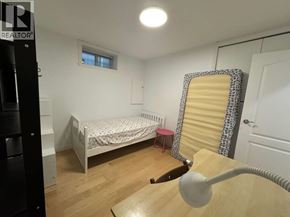 Vancouver apartment for rent - A bedroom with a bed, a desk with a lamp, and a window with blinds.