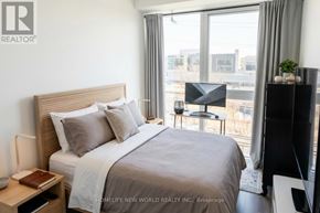 Toronto (Regent Park) condo for rent - A bedroom with a large bed and a view of the city.