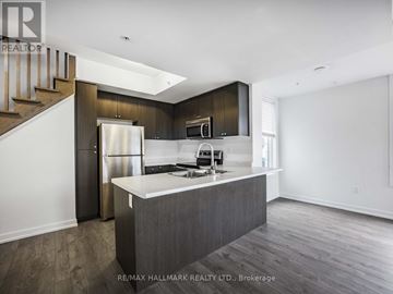 Pickering (Town Centre) townhouse for rent - A modern kitchen with dark wood cabinets and a white island.