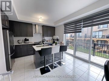 Whitby townhouse for rent - A kitchen with a refrigerator, sink, and a dining table with chairs.