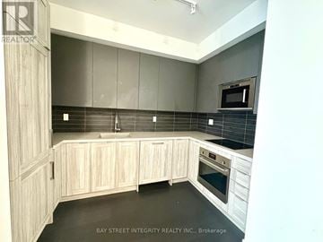 Vaughan (Concord) condo for rent - A kitchen with wooden cabinets and a black countertop.