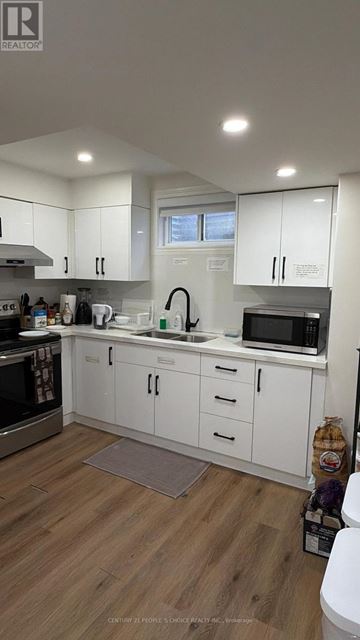 Toronto (West Humber-Clairville) apartment for rent - A kitchen with white cabinets and a wooden floor.