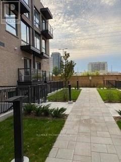 Toronto (Islington-City Centre West) condo for rent - A walkway with a metal railing and a grassy area on the side.
