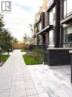 Toronto (Islington-City Centre West) condo for rent - A long, narrow walkway with a brick pattern is flanked by modern buildings.