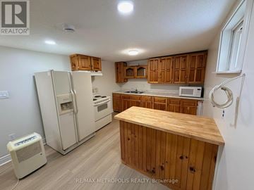 Clarington (Courtice) apartment for rent - A kitchen with wooden cabinets and a white fridge.