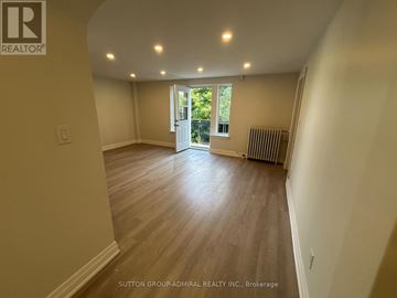 Toronto (Forest Hill South) multi-family for rent - A spacious room with wooden flooring and a sliding glass door leading to a balcony.