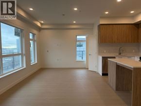New Westminster apartment for rent - A spacious room with wooden floors and a kitchen area with white cabinets.