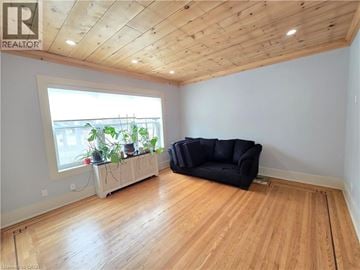 Hamilton apartment for rent - A living room with a black couch and wooden floors.
