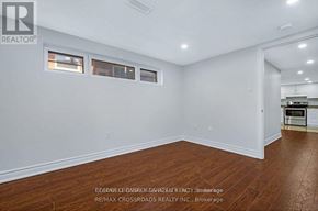 Ottawa apartment for rent - A room with white walls and wooden flooring, with a kitchen visible in the background.