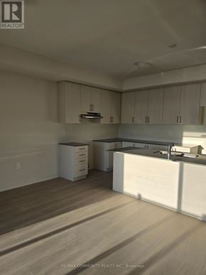 Clarington (Courtice) apartment for rent - A kitchen with white cabinets and a wooden floor.