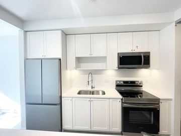Surrey apartment for rent - A kitchen with white cabinets and a black stove top oven.