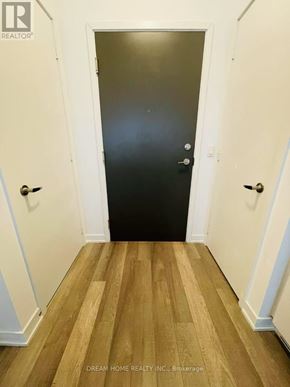 Toronto (Willowdale West) condo for rent - A black door is in the middle of a hallway with wood floors and white walls.