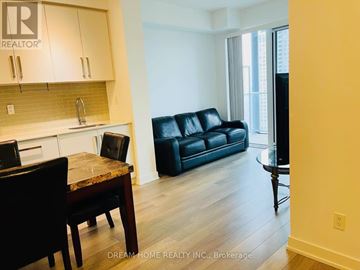Toronto (Willowdale West) condo for rent - A living room with a black leather couch and a wooden dining table.