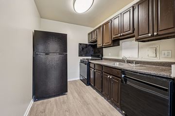 Riverdale apartment for rent - A kitchen with black appliances and brown cabinets.