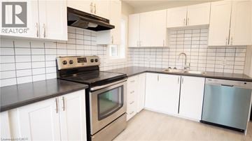 St. Catharines apartment for rent - A kitchen with white cabinets and black countertops.
