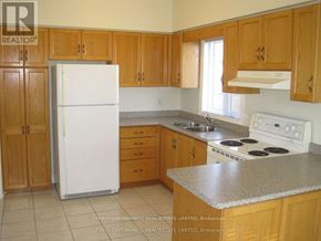 Toronto (Alderwood) multi-family for rent - A kitchen with wooden cabinets and a white fridge.