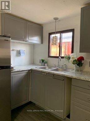 Clarington mobile home for rent - A kitchen with a sink, refrigerator, and cabinets.