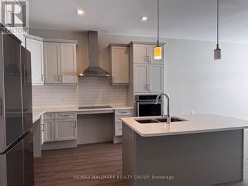 Brockville townhouse for rent - A kitchen with a refrigerator on the left and a sink with a stove top oven on the right.