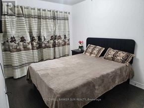 Whitby (Lynde Creek) apartment for rent - A bedroom with a bed, pillows, and a curtain with a floral pattern.