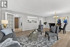 Stoney Creek condo for rent - A living room with a grey couch, a grey armchair, a coffee table, and a chandelier.