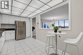 Stoney Creek condo for rent - A kitchen area with a refrigerator, a dining table with two chairs, and a window with a view of the outdoors.